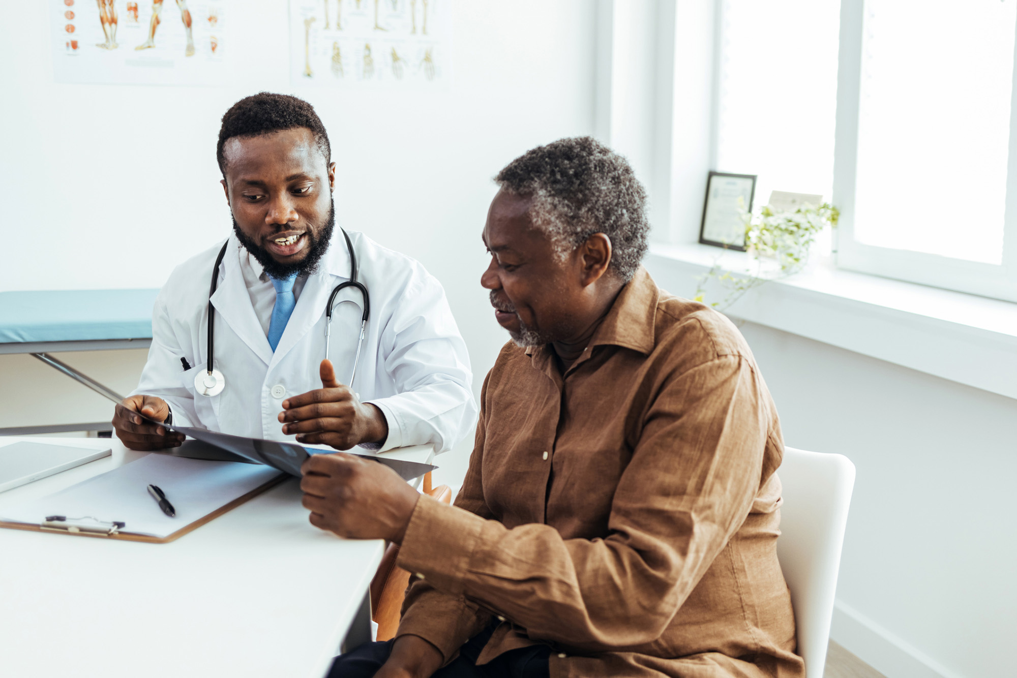 Male doctor and senior patient discussing scan results at the office.