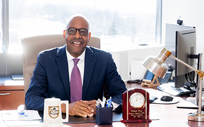 William Pryor sitting and smiling behind his desk