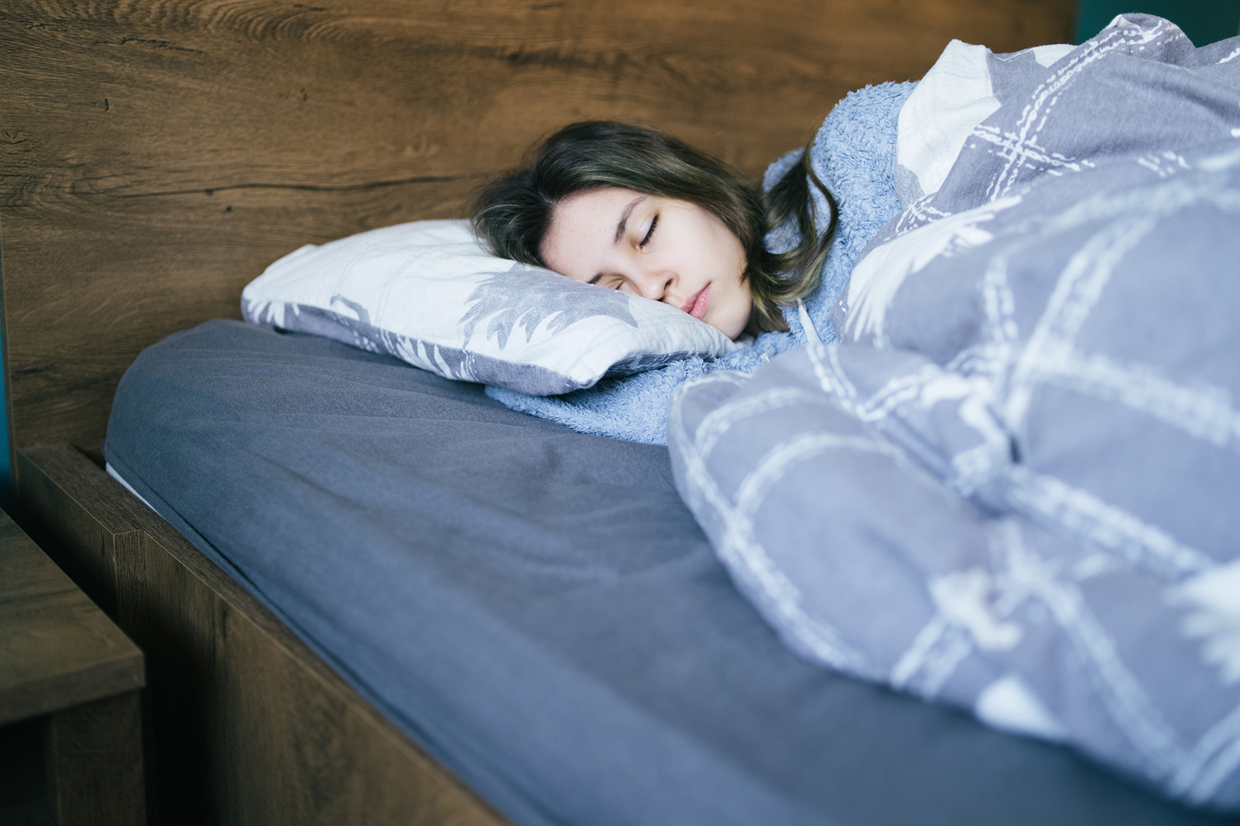 A woman tucked into covers in her bed