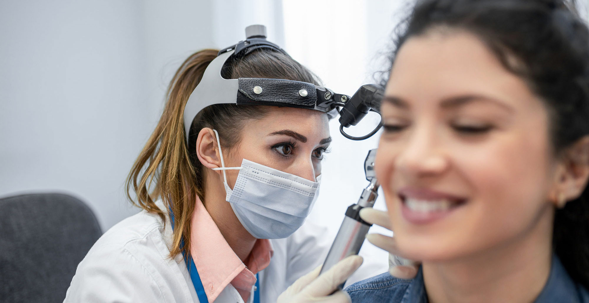 Otolaryngologist doctor checking woman's ear using otoscope or auriscope at medical clinic