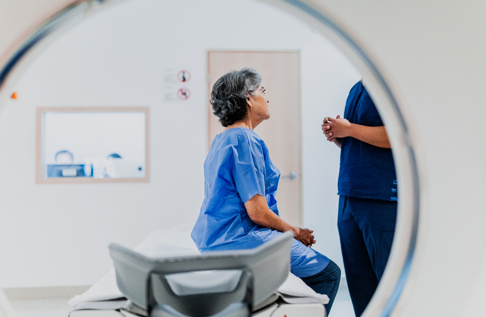 Senior woman talking to a nurse on a MRI tomography at hospital