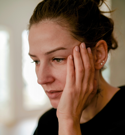 A young woman is stressed and brings her hand to her face.