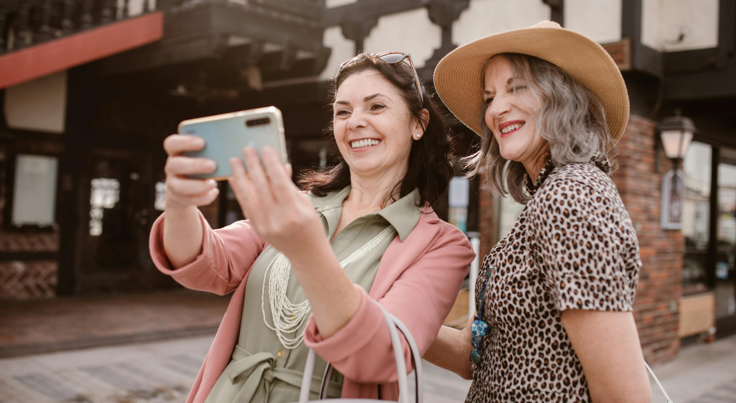 Two women in their 50s or 60s traveling together, smiling and taking a selfie