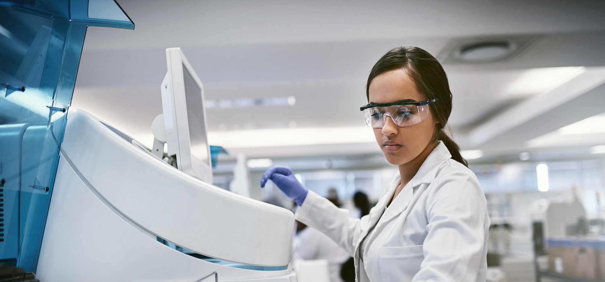 A female medical researcher operates medical research equipment in a lab setting