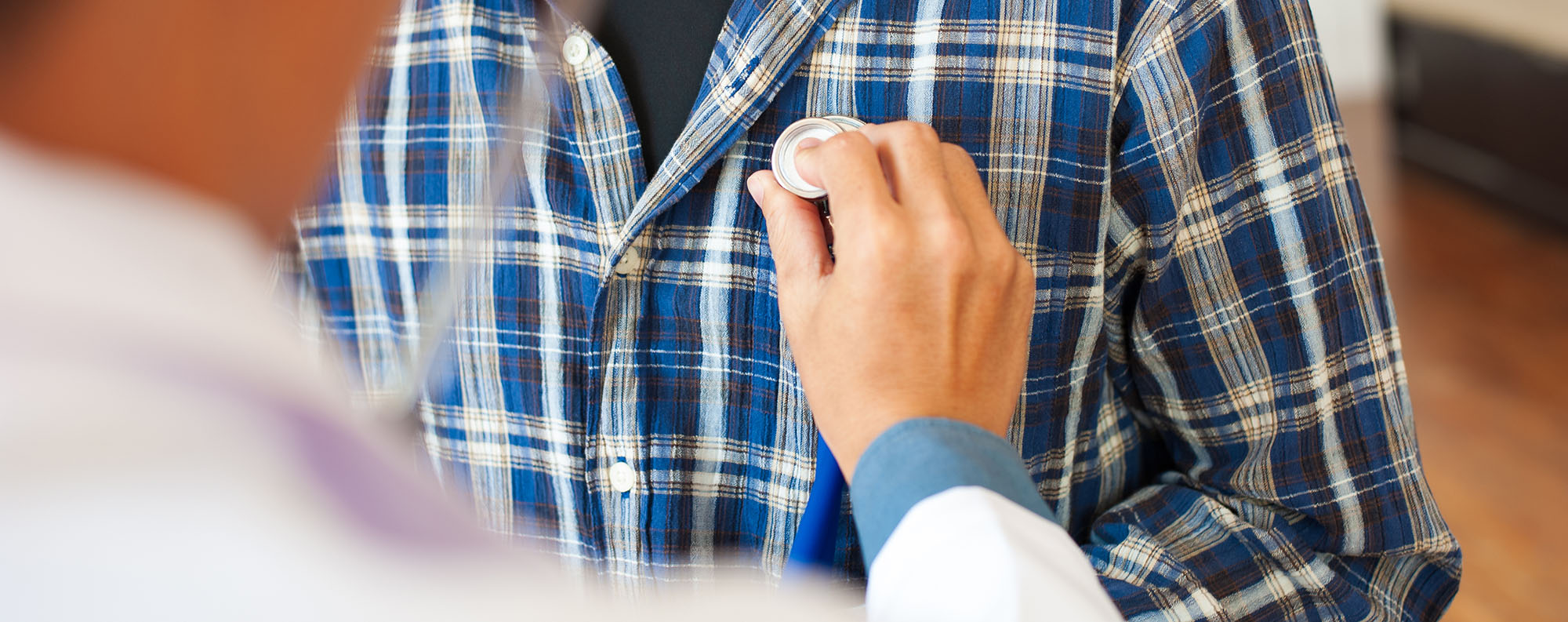 Doctors use a stethoscope on a male patient's chest