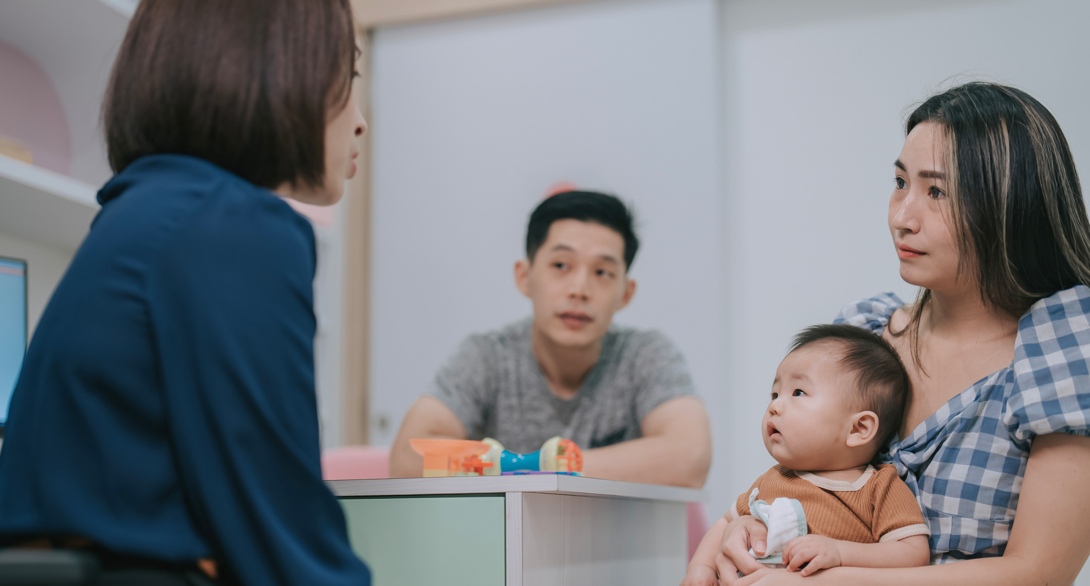 Asian Chinese female Pediatrician explaining to parents of baby boy in clinic