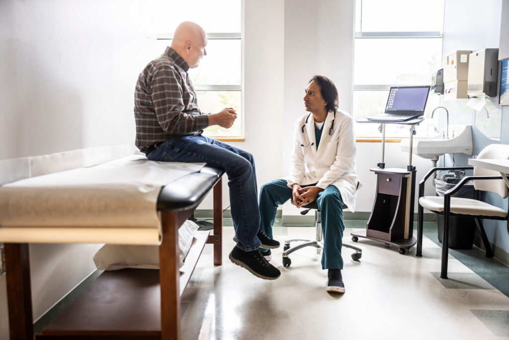 A senior man consults with a younger male doctor in a bright doctor's office