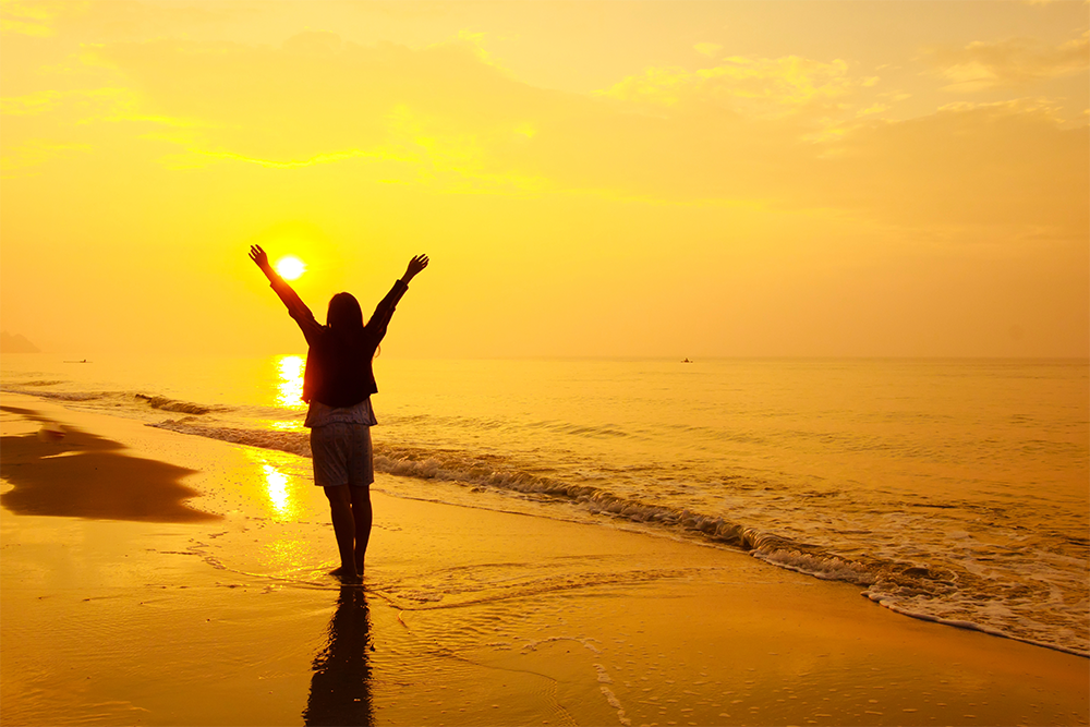 woman walking freely on the beach at sunset